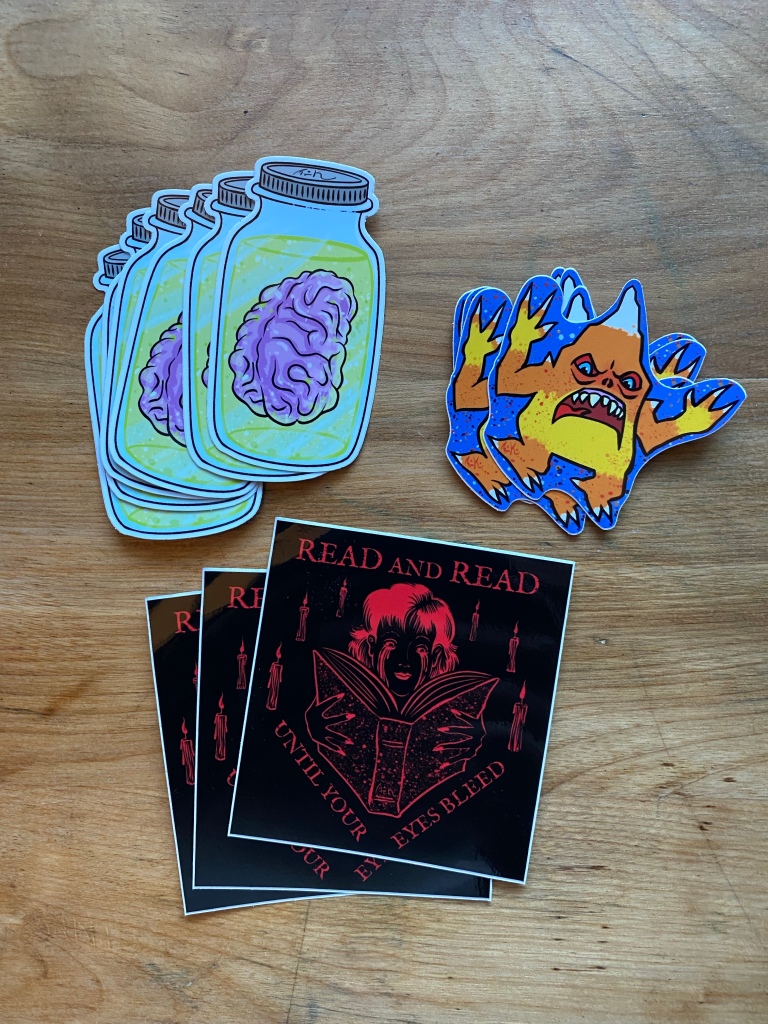 stickers designed by M. R. Kessell including Brain in a jar and a candy corn kaiju known as cornzilla 