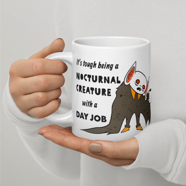 closeup photo of woman holding Batboy mug in hands. Text reads: It's tough being a nocturnal creature with a day job.